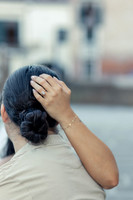 Close-up of a woman adjusting her hair, lost in thought.