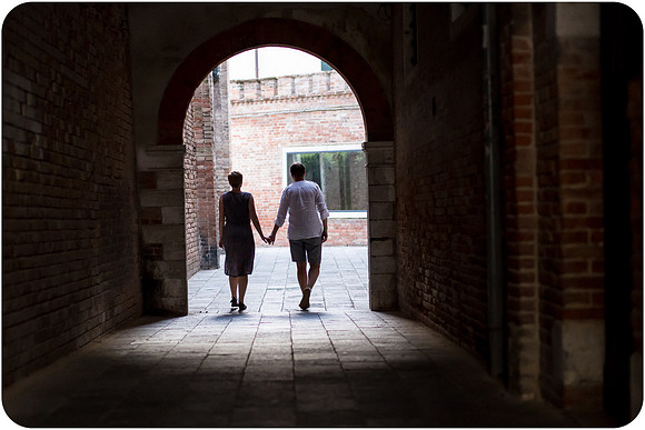 Lesbian couple walking under the archways of Venice.