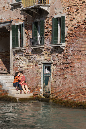 Couple relaxing by the Venetian canal during autumn engagement.