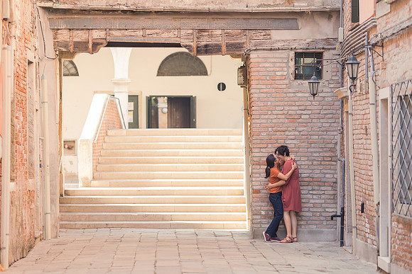 Couple embracing by a Venetian staircase during autumn engagement.