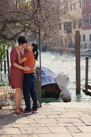 Couple sharing a glance and a smile in the Venetian sun during autumn engagement.