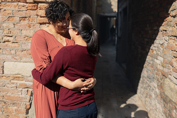 Couple hugging by a Venetian brick wall during autumn engagement.