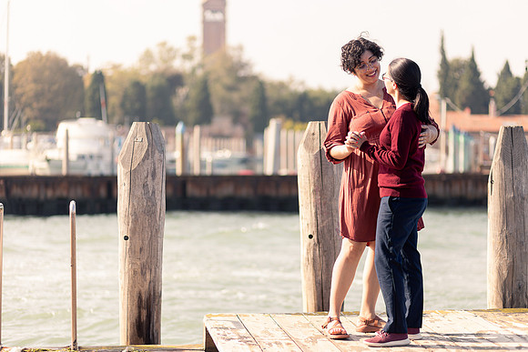 Couple embracing by the Venetian lagoon during autumn engagement.