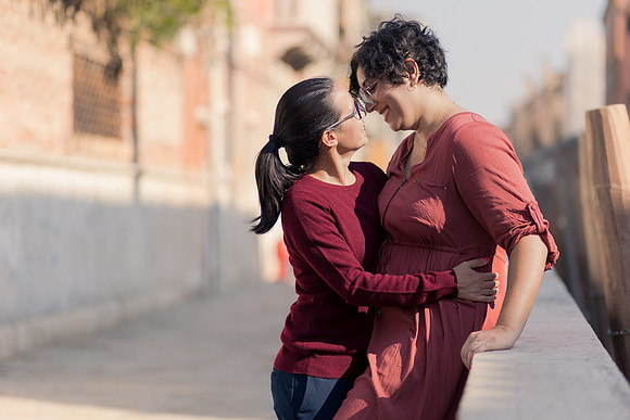 Couple kissing by the canal in Venice during autumn engagement.