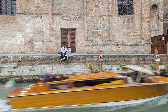 A passing boat creates motion behind the newly engaged couple.