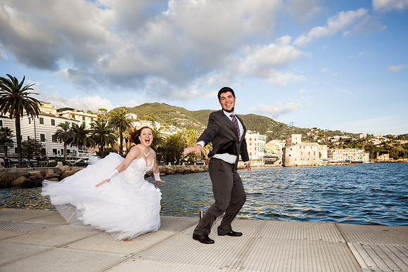 Bride and groom dancing on a dock by the sea.