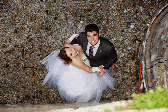Aerial shot of bride and groom lying on the ground with stone walls around them.