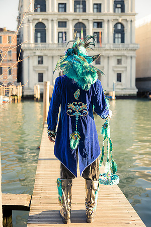 Couple in ornate handmade costumes posing on a pier in Venice