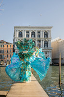 A wide shot of a couple in bespoke carnival attire near the water