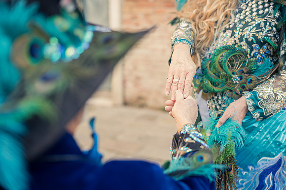 Couple in elaborate handmade costumes walking along the Grand Canal
