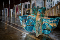 Couple in vibrant custom costumes by the edge of a Venetian canal