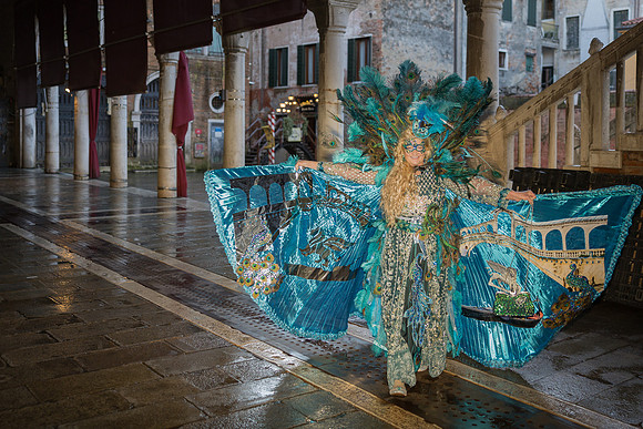 Couple in vibrant custom costumes by the edge of a Venetian canal