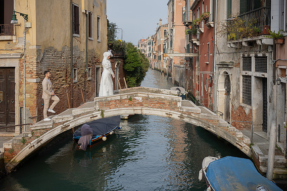Woman in a white dress standing on Ponte Chiodo in Venice.