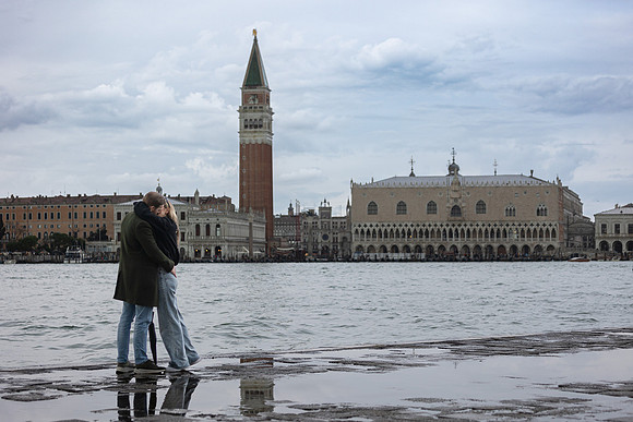 A newly engaged couple stands by the water with San Giorgio Maggiore as their backdrop.