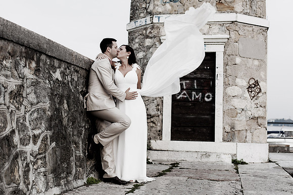 Bride and groom sharing a kiss by a stone wall.