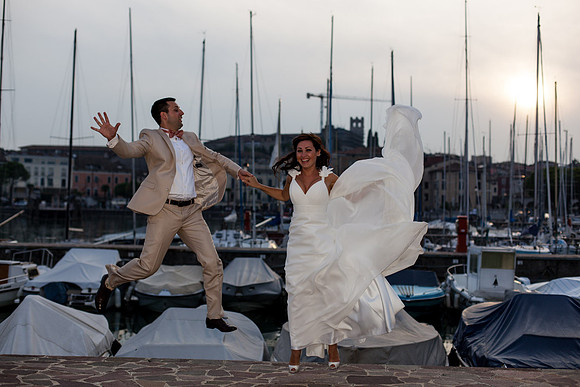 Bride and groom jumping with joy near the marina.