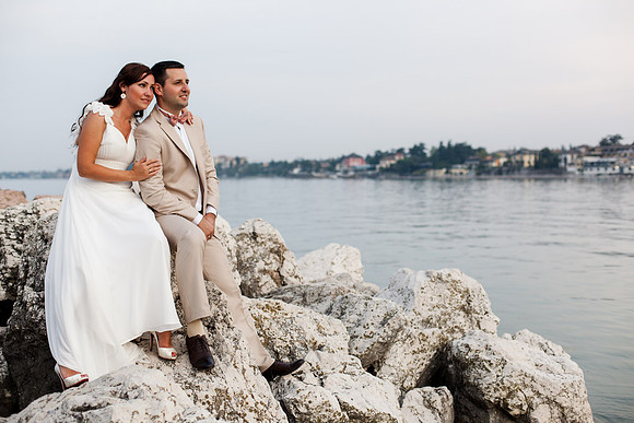 Bride and groom sitting on rocks, enjoying a quiet moment at sunset.