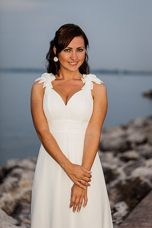Bride posing elegantly by the water.