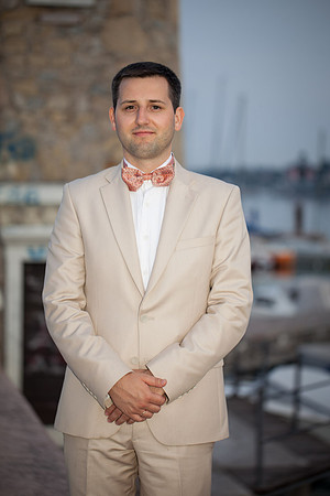 Groom standing in a light-colored suit for a portrait.