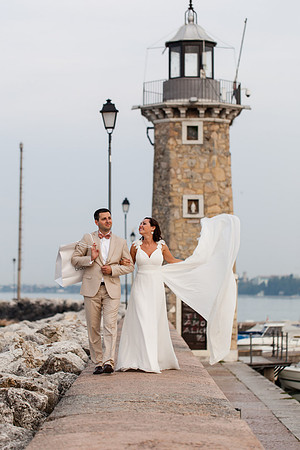 Bride and groom with veil flowing near the lighthouse.