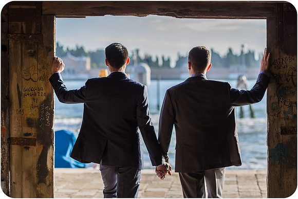 Couple holding hands and looking at the Venice skyline.