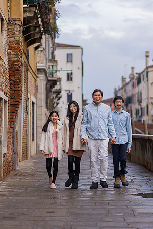Family of four walking through a Venetian street in winter.