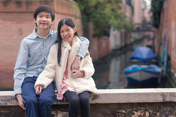 Father and daughter sitting by the canal in Venice during winter.