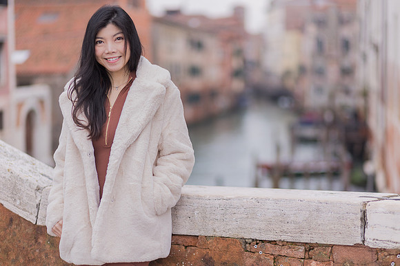 Young girl standing by a Venetian canal in winter.