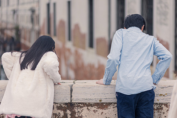 Brother and sister looking over a Venetian canal in winter.