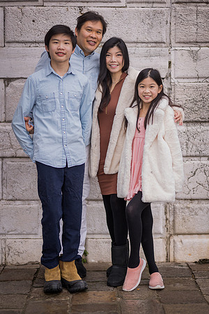 Family of four posing against a Venetian wall in winter.