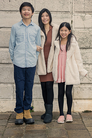 Family posing in front of a stone building in Venice during winter.