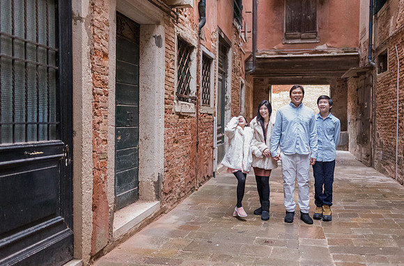 Family walking down a narrow street in Venice during winter.