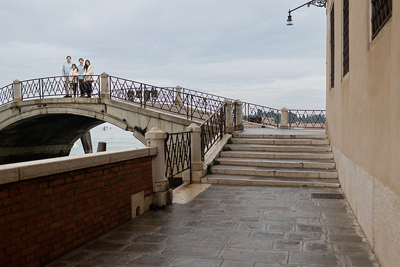 Family walking across a stone bridge in Venice during winter.