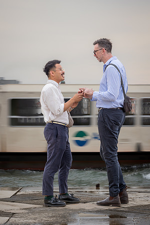 Engaged gay couple standing and holding hands after the proposal.