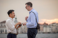 Two men smiling at each other holding hands after getting engaged.
