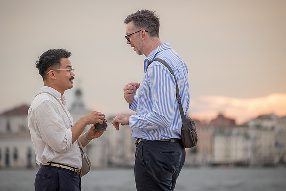 Two men smiling at each other holding hands after getting engaged.