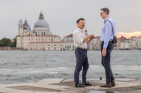 Gay couple standing together while one holds the engagement ring box.
