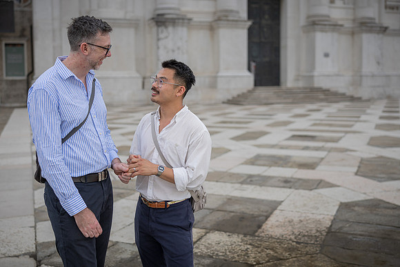 Engaged couple walking and smiling in a Venetian courtyard.