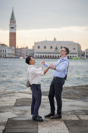 Couple playfully dancing on San Giorgio island with St. Mark's in the background.