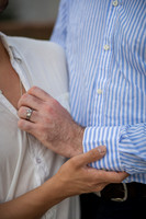 Close up showing a hand with an engagement ring resting on a blue shirt.