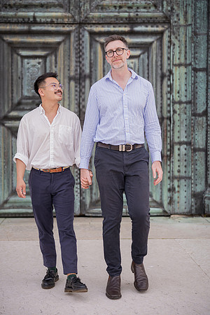 Engaged couple walking in front of a grand green historic door.