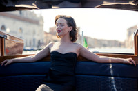 Actress Sunny Mittmann smiling in a wooden water taxi heading to the Excelsior Hotel.