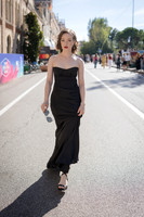 Sunny Mittmann in a black evening dress walking outside during the day.