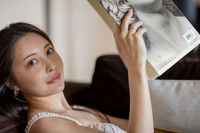 Close up of a woman holding a magazine and relaxing on a sofa.