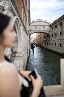 Over the shoulder portrait of a woman with the Bridge of Sighs behind her.