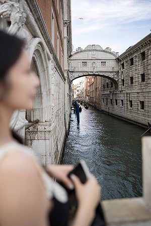 Over the shoulder portrait of a woman with the Bridge of Sighs behind her.