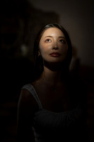 Dark portrait of a woman looking up with dramatic lighting.