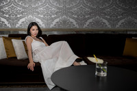 Woman in a white dress sitting on a large dark sofa in a modern room.