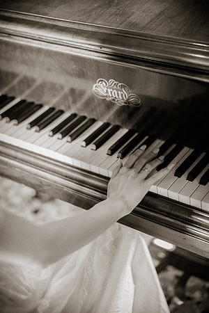 Close up of hands playing a piano in black and white tones.