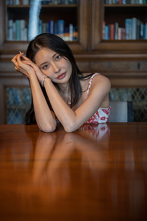 Close up of a woman leaning on a table in a library setting.